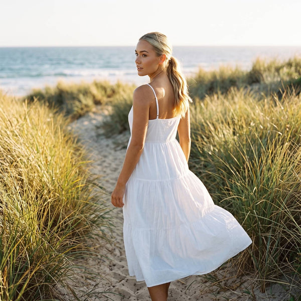 Woman in a white tiered cotton sundress on a coastal path in the late afternoon light